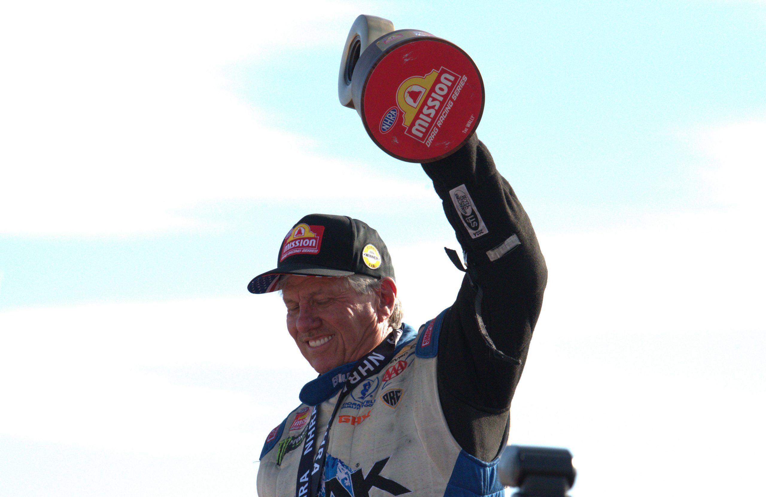 John Force hoists the New England Nationals Wally after his second win of the season.